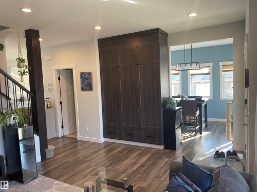 The interior features dark wood-look flooring, recessed lighting, and a prominent dark-toned storage cabinet - 15220 105 Avenue, Edmonton, AB - Indoor