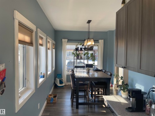 This dining area features several windows, a modern light fixture, and dark wood cabinetry - 15220 105 Avenue, Edmonton, AB - Indoor Photo Showing Dining Room