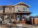 The property features a front entrance with a white door, a covered porch with wooden supports, and a small front yard with a tree - 15220 105 Avenue, Edmonton, AB  - Outdoor With Deck Patio Veranda 