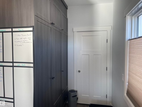 This area features tall, built-in storage cabinets with dark hardware, a white paneled door with a simple trim, and a window with a cellular blind - 15220 105 Avenue, Edmonton, AB - Indoor Photo Showing Other Room