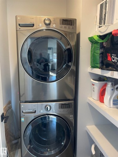 Laundry area featuring a stacked washer and dryer, and wall-mounted shelving - 15220 105 Avenue, Edmonton, AB - Indoor Photo Showing Laundry Room