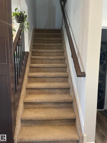 Staircase featuring carpeted steps and dark wood handrails with black balusters - 15220 105 Avenue, Edmonton, AB - Indoor Photo Showing Other Room