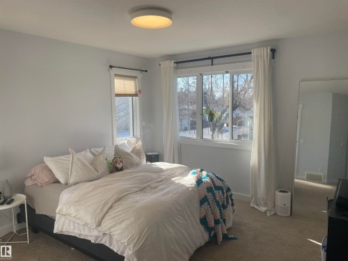 This room features large windows with blinds and curtains, a ceiling light fixture, and carpeted flooring - 15220 105 Avenue, Edmonton, AB - Indoor Photo Showing Bedroom