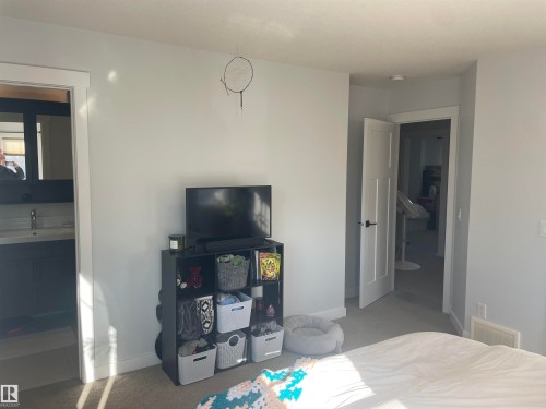 Bedroom featuring light-colored carpeting, white walls, and a white door with a black handle - 15220 105 Avenue, Edmonton, AB - Indoor Photo Showing Bedroom