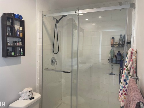 The bathroom features a spacious walk-in shower with clear glass doors and white tiled walls - 15220 105 Avenue, Edmonton, AB - Indoor Photo Showing Bathroom