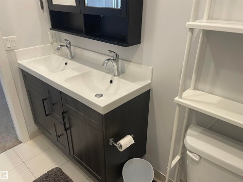 Bathroom featuring a double vanity with dark wood cabinetry, white countertops, and chrome faucets - 15220 105 Avenue, Edmonton, AB - Indoor Photo Showing Bathroom