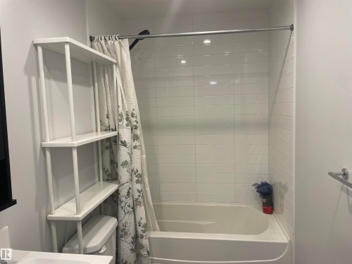 Bathroom featuring a white bathtub, white tiled shower walls, and a white shelving unit - 15220 105 Avenue, Edmonton, AB - Indoor Photo Showing Bathroom