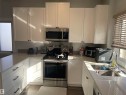 The kitchen features white cabinetry, stainless steel appliances, and a double basin sink - 15220 105 Avenue, Edmonton, AB  - Indoor Photo Showing Kitchen 