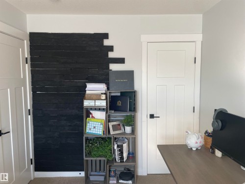 This versatile room features a black accent wall with horizontal paneling and a light-colored door with a rectangular panel design - 15220 105 Avenue, Edmonton, AB - Indoor Photo Showing Other Room