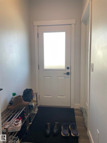 Entryway featuring a white door with a frosted glass panel, dark hardware, and light wood-style flooring - 15220 105 Avenue, Edmonton, AB - Indoor Photo Showing Other Room