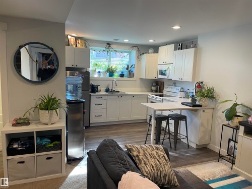 This property features a well-appointed kitchen with white cabinetry and integrated appliances, including a stove and microwave - 15220 105 Avenue, Edmonton, AB - Indoor Photo Showing Kitchen