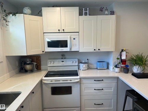 Kitchen featuring white shaker style cabinetry with black hardware, a built-in microwave, and an electric stove - 15220 105 Avenue, Edmonton, AB - Indoor Photo Showing Kitchen