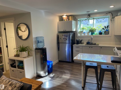 The property features a kitchen area with white cabinetry, stainless steel appliances, and a window above the sink - 15220 105 Avenue, Edmonton, AB - Indoor Photo Showing Kitchen