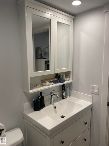 Bathroom featuring a white vanity with two drawers, a white sink with a chrome faucet, and a white mirrored cabinet above - 15220 105 Avenue, Edmonton, AB - Indoor Photo Showing Bathroom