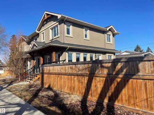 The property features a stucco exterior, dark roof, and white-framed windows - 15220 105 Avenue, Edmonton, AB - Outdoor