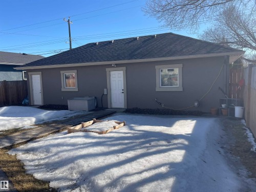 The property features a dark gray exterior with a dark shingle roof, white trim around the windows and doors, and a wooden fence - 15220 105 Avenue, Edmonton, AB - Outdoor