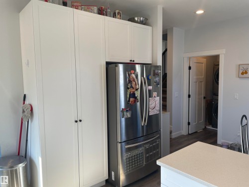 The property features a kitchen with white cabinetry and a stainless steel refrigerator - 15220 105 Avenue, Edmonton, AB - Indoor