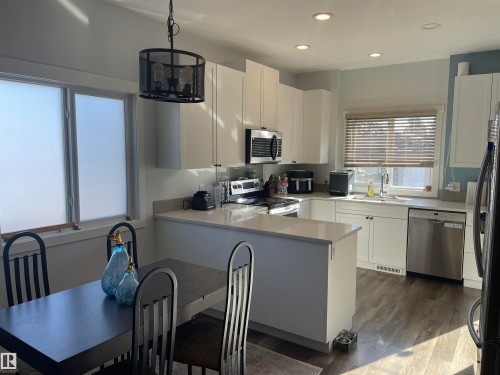 The kitchen features light-toned cabinetry, stainless steel appliances, and a central island with a light-colored countertop - 15220 105 Avenue, Edmonton, AB - Indoor