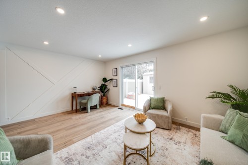 The living area features recessed lighting, light wood-style flooring, and a sliding glass door leading to an outdoor space - 125 Woodborough Way, Edmonton, AB - Indoor Photo Showing Living Room