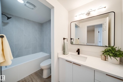 Bathroom featuring a white vanity with a rectangular sink, a black framed mirror, and a shower-tub combination with light grey tiling - 125 Woodborough Way, Edmonton, AB - Indoor Photo Showing Bathroom