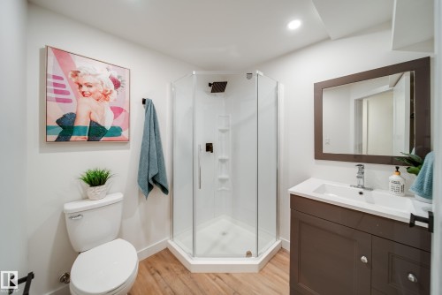 Bathroom featuring a corner shower with a glass enclosure, a vanity with a white countertop and sink, and wood-look flooring - 125 Woodborough Way, Edmonton, AB - Indoor Photo Showing Bathroom