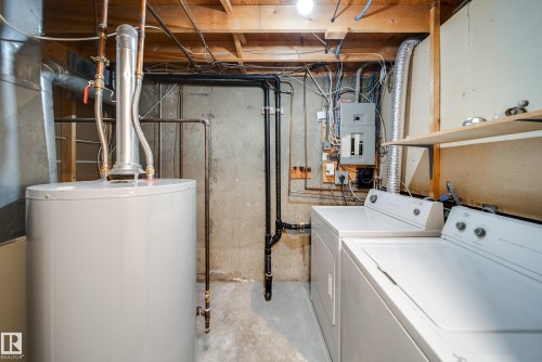 The utility area features a water heater, laundry appliances, and exposed overhead joists - 125 Woodborough Way, Edmonton, AB - Indoor