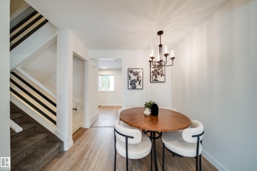 The property features a staircase with carpeted treads and a railing with horizontal black and white balusters - 125 Woodborough Way, Edmonton, AB - Indoor Photo Showing Dining Room