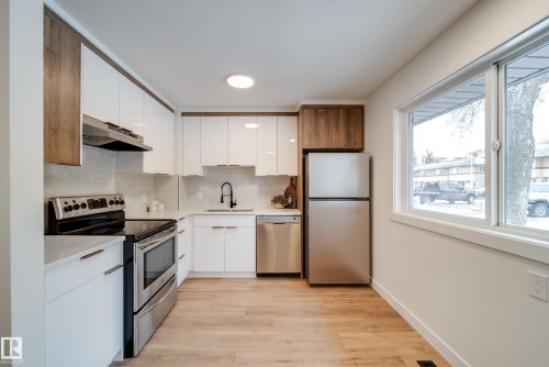 Modern kitchen featuring white and wood-grain cabinetry, stainless steel appliances, and light-toned flooring - 125 Woodborough Way, Edmonton, AB - Indoor Photo Showing Kitchen