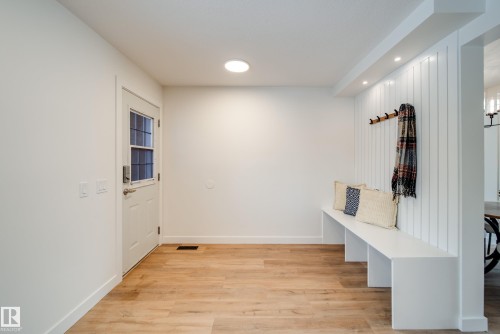 Entryway featuring wood-look flooring, a white door with glass panels, and a built-in white bench with vertical paneling - 125 Woodborough Way, Edmonton, AB - Indoor Photo Showing Other Room
