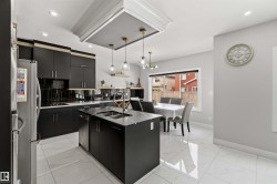 The kitchen features a functional island with an undermount sink, dark cabinetry, and white tile flooring - 
