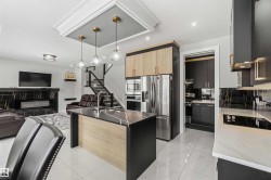Open concept interior featuring a modern kitchen island with a sink, a stainless steel refrigerator, and a dark marble-style backsplash - 