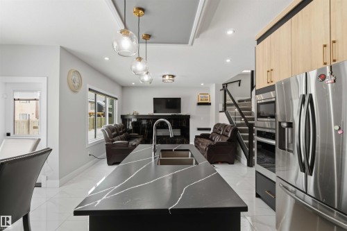 The kitchen features a large island with a dark countertop and an undermount sink - 1520 151 Avenue, Edmonton, AB - Indoor Photo Showing Kitchen With Double Sink With Upgraded Kitchen