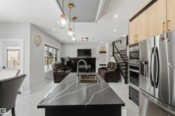 The kitchen features a large island with a dark countertop and an undermount sink - 