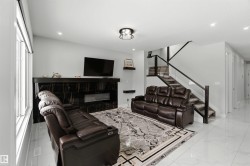 The living area features a modern fireplace with a black marble-style surround, large windows, and sleek tile flooring - 