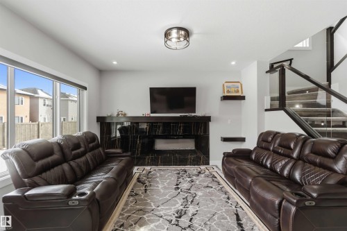 The living area features a dark marble-style fireplace, recessed lighting, and a large window - 1520 151 Avenue, Edmonton, AB - Indoor Photo Showing Living Room