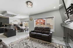 This open-concept living area features light-toned walls, recessed lighting, and a contemporary ceiling light fixture - 