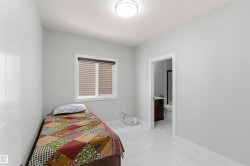 Bright room featuring a window with blinds, a ceiling light fixture, and white tile flooring - 