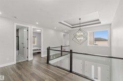 The property features a hallway with hardwood flooring, recessed lighting, and a modern chandelier - 