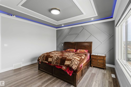 This room features a contemporary accent wall with a geometric pattern, hardwood-style flooring, and a large window providing natural light - 1520 151 Avenue, Edmonton, AB - Indoor Photo Showing Bedroom
