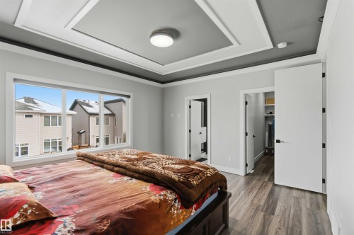 This room features a tray ceiling with a central light fixture, a large window, and durable flooring - 1520 151 Avenue, Edmonton, AB - Indoor Photo Showing Bedroom