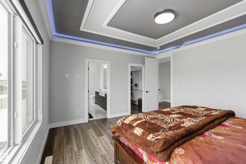 Bedroom featuring a tray ceiling with integrated lighting, a window, and wood-style flooring - 1520 151 Avenue, Edmonton, AB - Indoor Photo Showing Bedroom