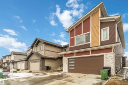 The property features a modern exterior with a brown garage door, light-colored stone accents, and a distinctive sloped roofline - 