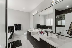 Modern bathroom featuring a dual vanity with rectangular sinks, black cabinetry, and light-colored countertops - 