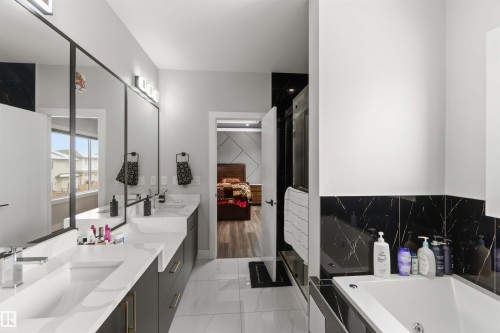 This bathroom features a double vanity with ample counter space, a large mirror, and contemporary light fixtures - 1520 151 Avenue, Edmonton, AB - Indoor Photo Showing Bathroom