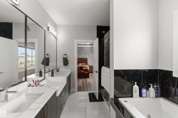 This bathroom features a double vanity with ample counter space, a large mirror, and contemporary light fixtures - 