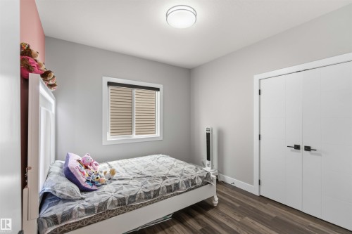 This room features durable plank flooring, a window with blinds, and white bi-fold closet doors with black hardware - 1520 151 Avenue, Edmonton, AB - Indoor Photo Showing Bedroom