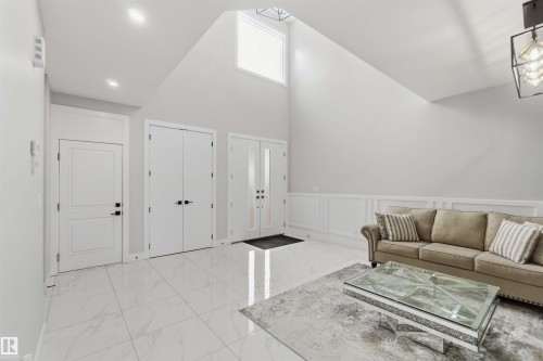 The property features high vaulted ceilings with a transom window providing natural light, recessed lighting, and white tile flooring - 1520 151 Avenue, Edmonton, AB - Indoor