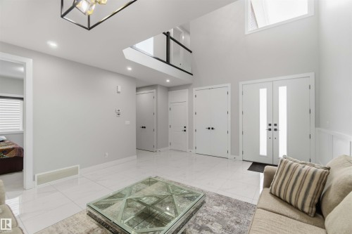 The property entrance features a double door with vertical glass inserts, high ceilings, and white tile flooring - 1520 151 Avenue, Edmonton, AB - Indoor Photo Showing Other Room