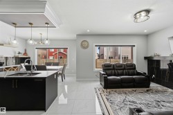 Open concept living area featuring light-toned tile flooring, recessed lighting, and large windows providing natural light - 