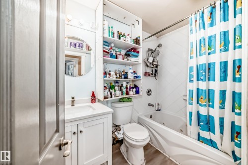 The bathroom features a vanity with an undermount sink, a toilet, and a bathtub with an overhead shower - 16305 107A Ave, Edmonton, AB - Indoor Photo Showing Bathroom